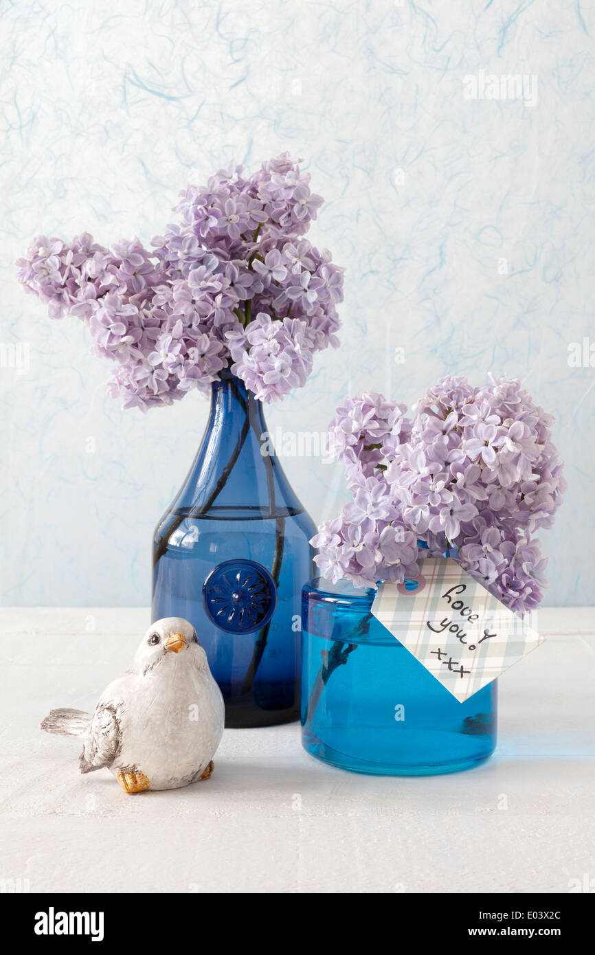 Still life with Lilacs in blue vases, a little bird and a card with the ...