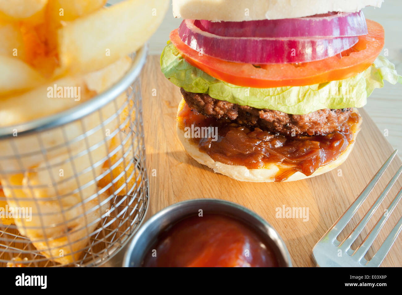 Classic burger and salad with side order of French fries or chips and tomato ketchup on a wooden
