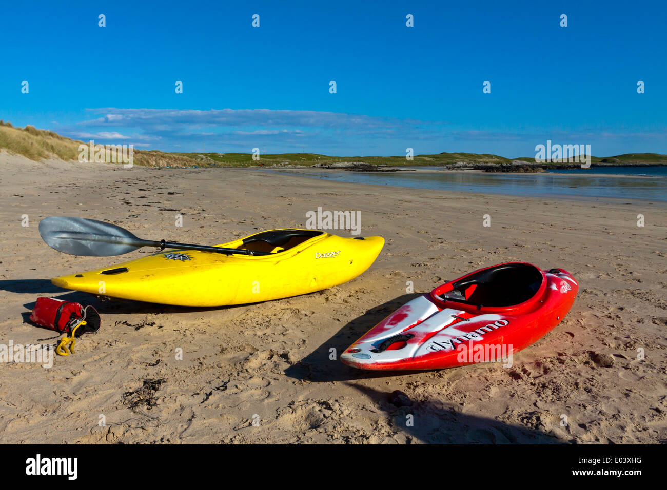Red and yellow kayaks on a deserted sandy beach with sea and sky in the background Stock Photo