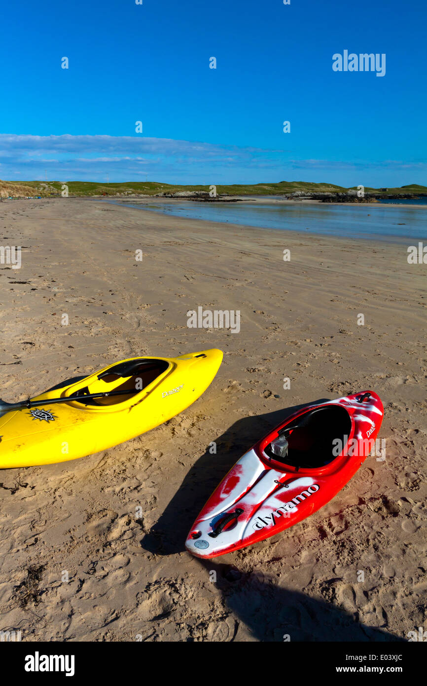 Red and yellow kayaks on a deserted sandy beach with sea and sky in the background Stock Photo