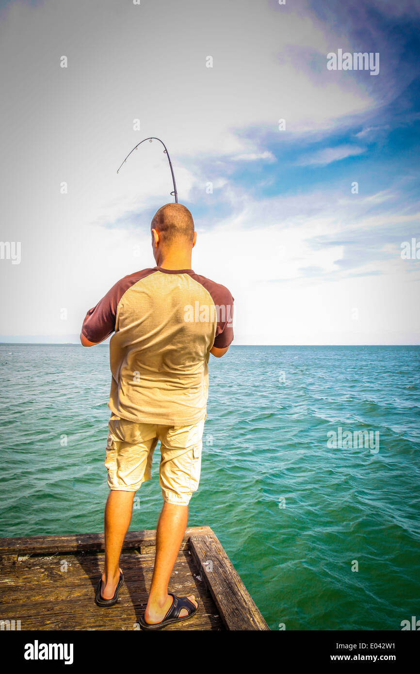 Fisherman Reeling In His Catch Which Fights Against Being Landed As The