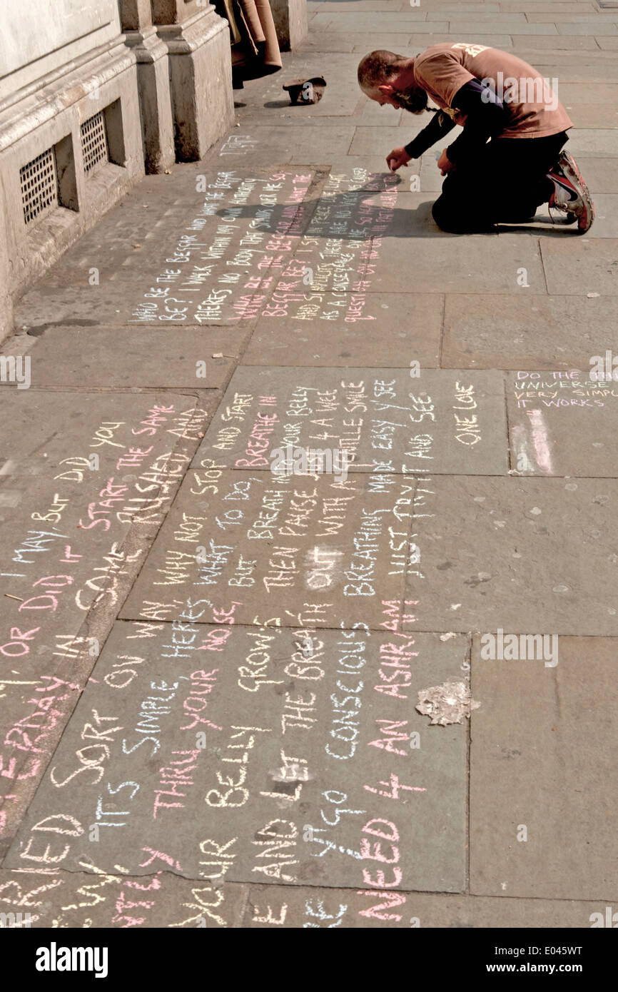 A man chalks philosophical thoughts onto the pavement in Camden Town, London. Stock Photo