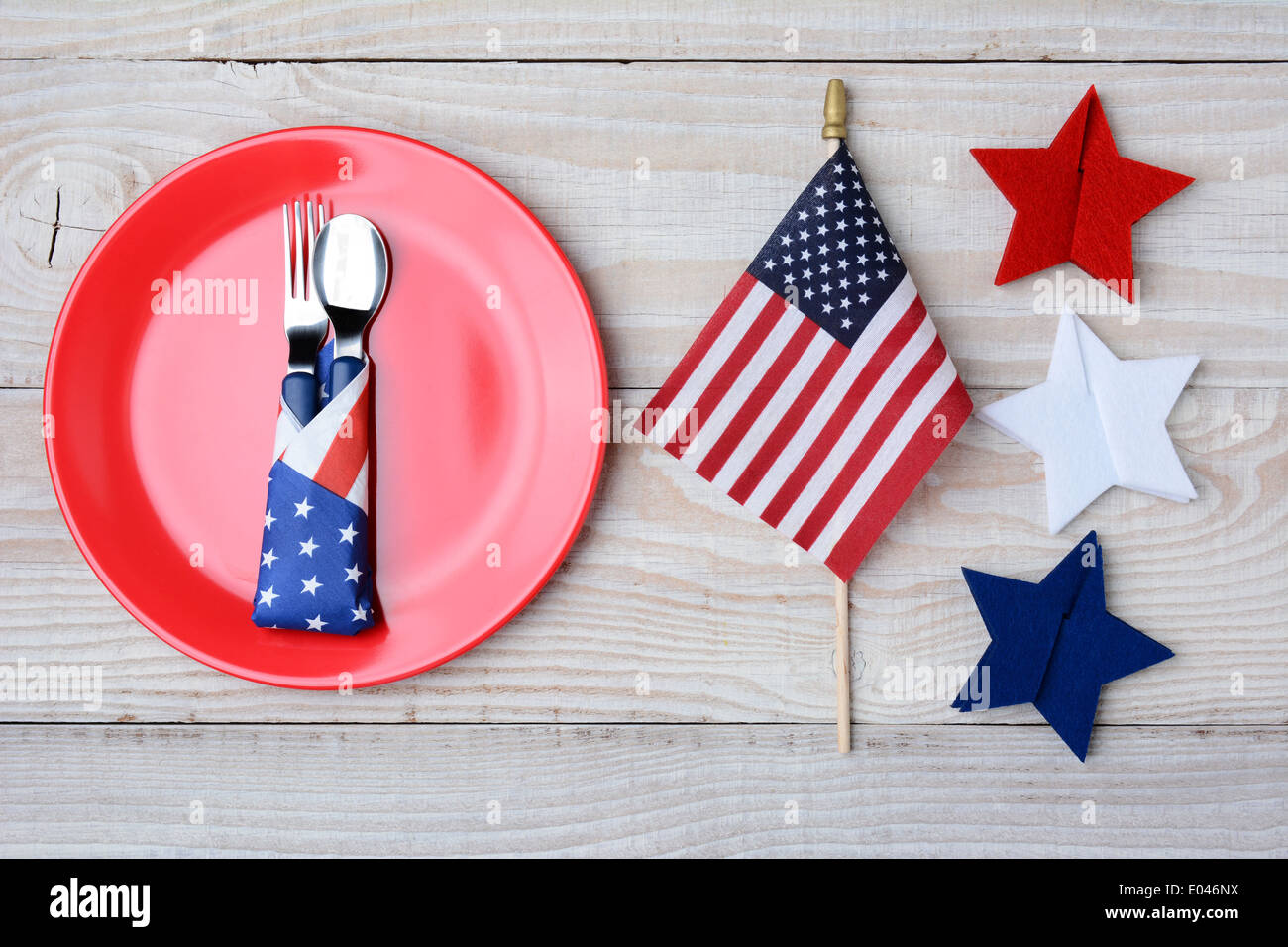 A picnic table ready for a 4th of July picnic. A red plate with fork and spoon, American Flag and felt stars decorate the table. Stock Photo