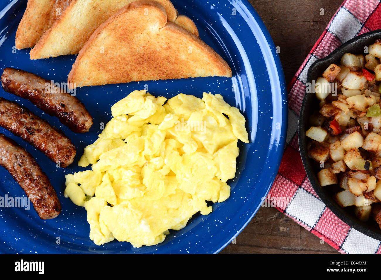 High angle shot of a country style scramble egg breakfast on a rustic wooden restaurant table. Stock Photo