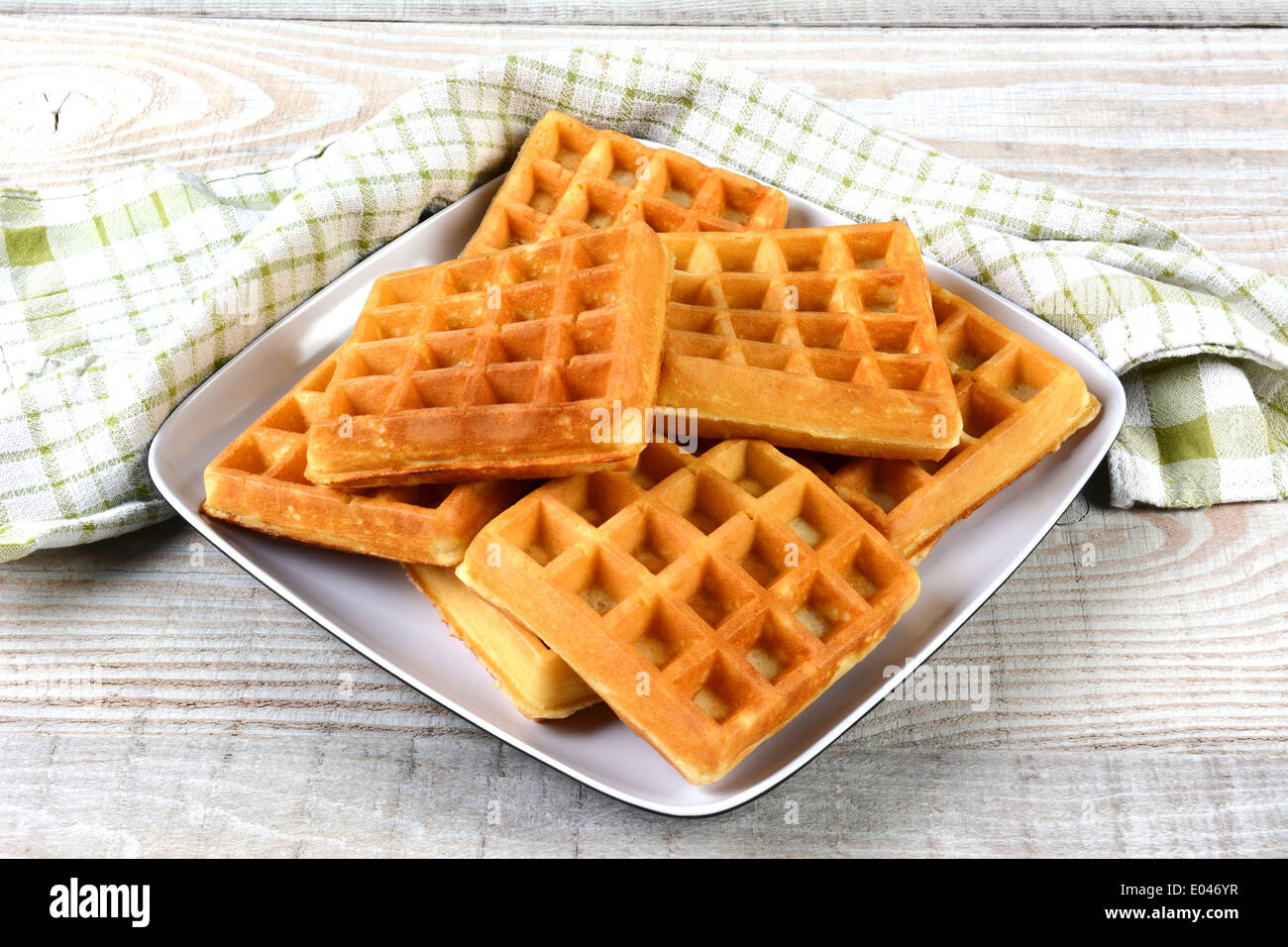 A plate of fresh made waffles on a rustic farmhouse style table. Stock Photo