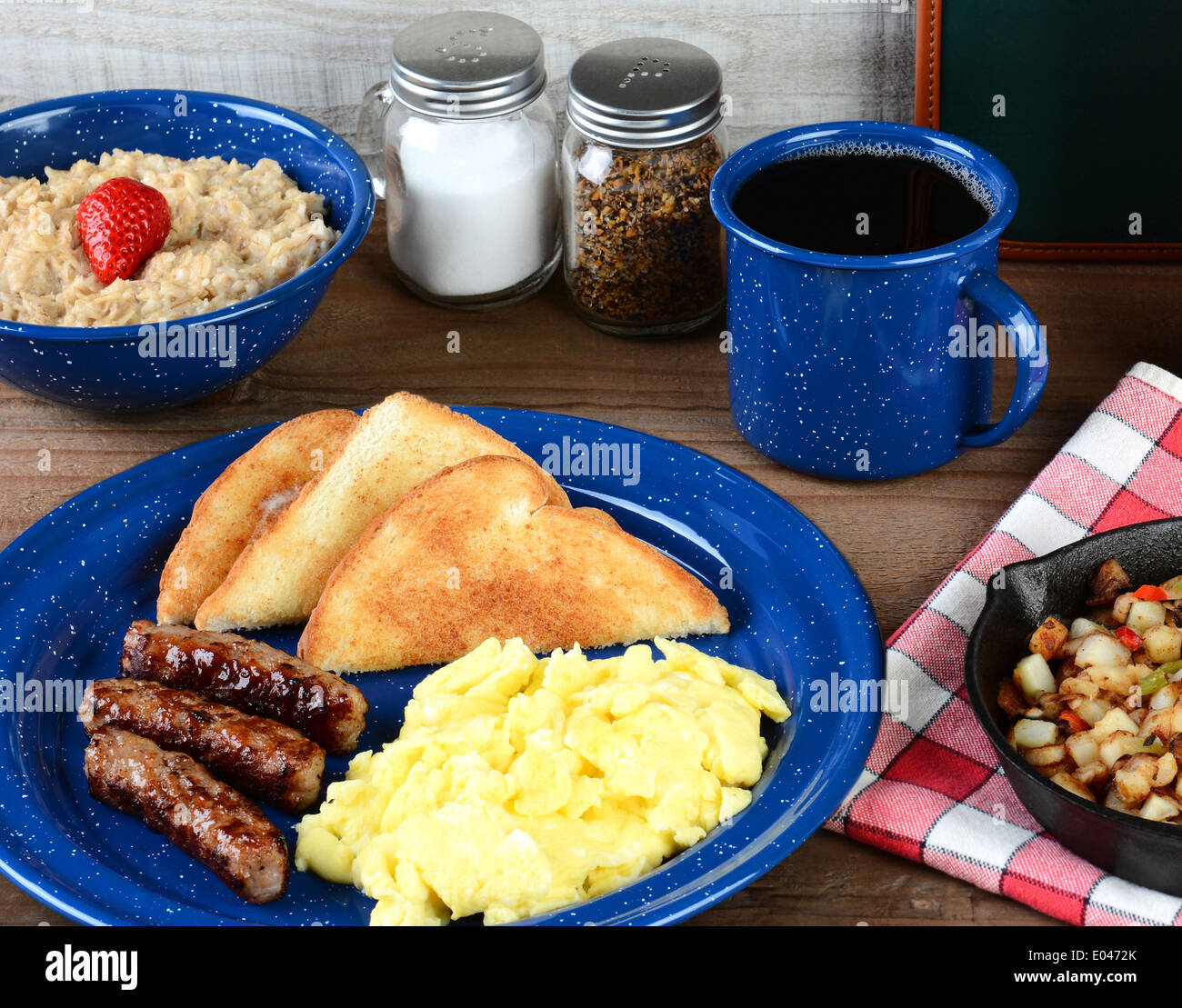 A country style scrambled egg breakfast on a rustic wooden restaurant table. Eggs, sausage links, toast Stock Photo