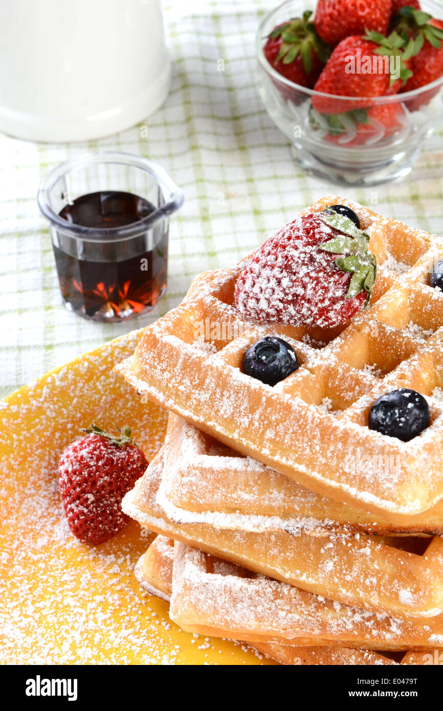 Waffles with strawberries and blueberries covered with powdered sugar Stock Photo