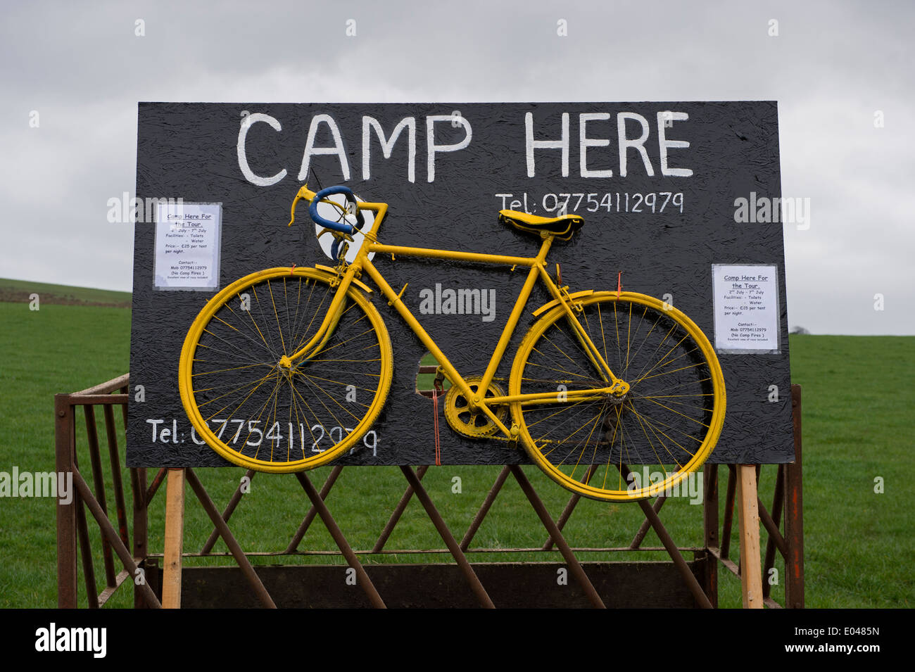 Eye-catching advertising sign & yellow bike in field, on route of 'Grand Depart' to advertise pop-up campsite - Skipton, North Yorkshire, England, UK. Stock Photo