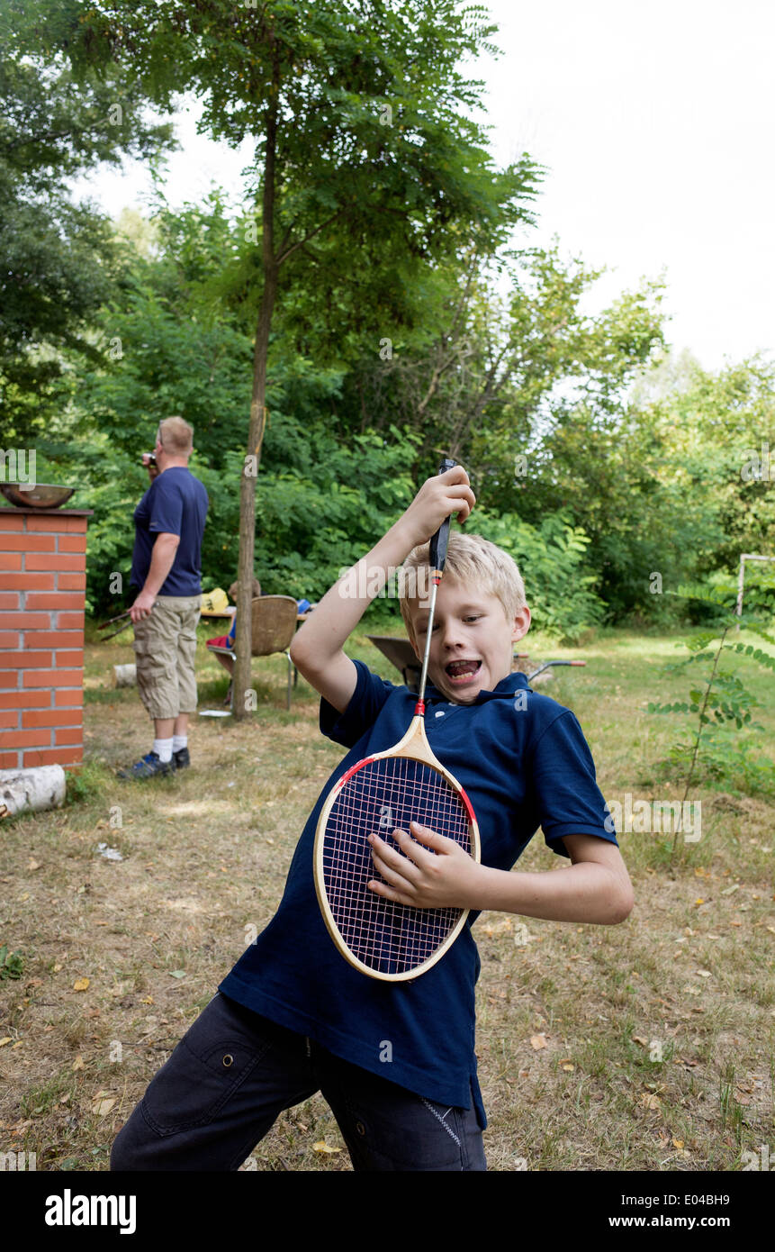 Polish boy age 10 playing air badminton guitar while father works at