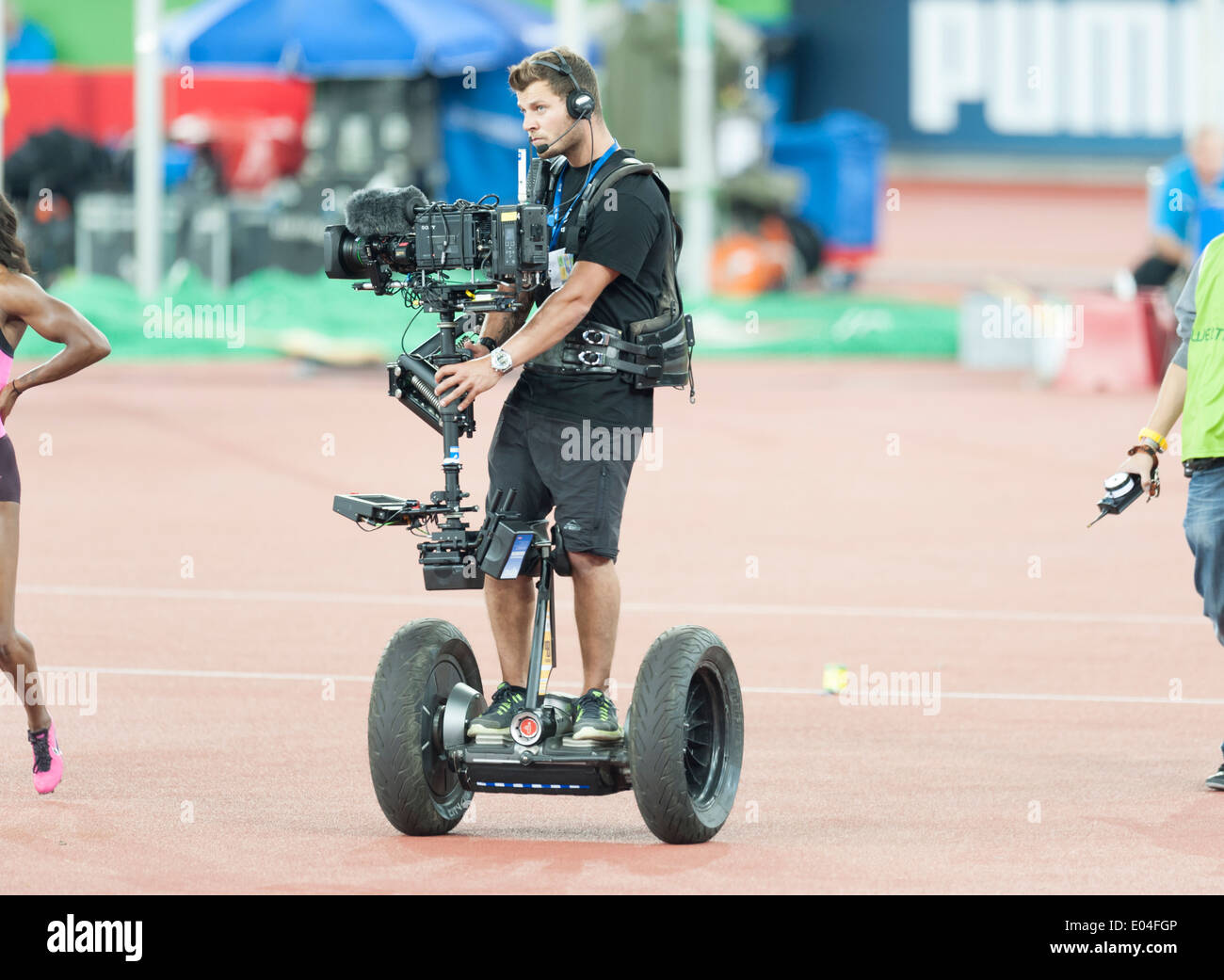 Camera operator standing on a Segway and equipped with Steadicam camera stabilizing system during an athletics meeting Stock Photo