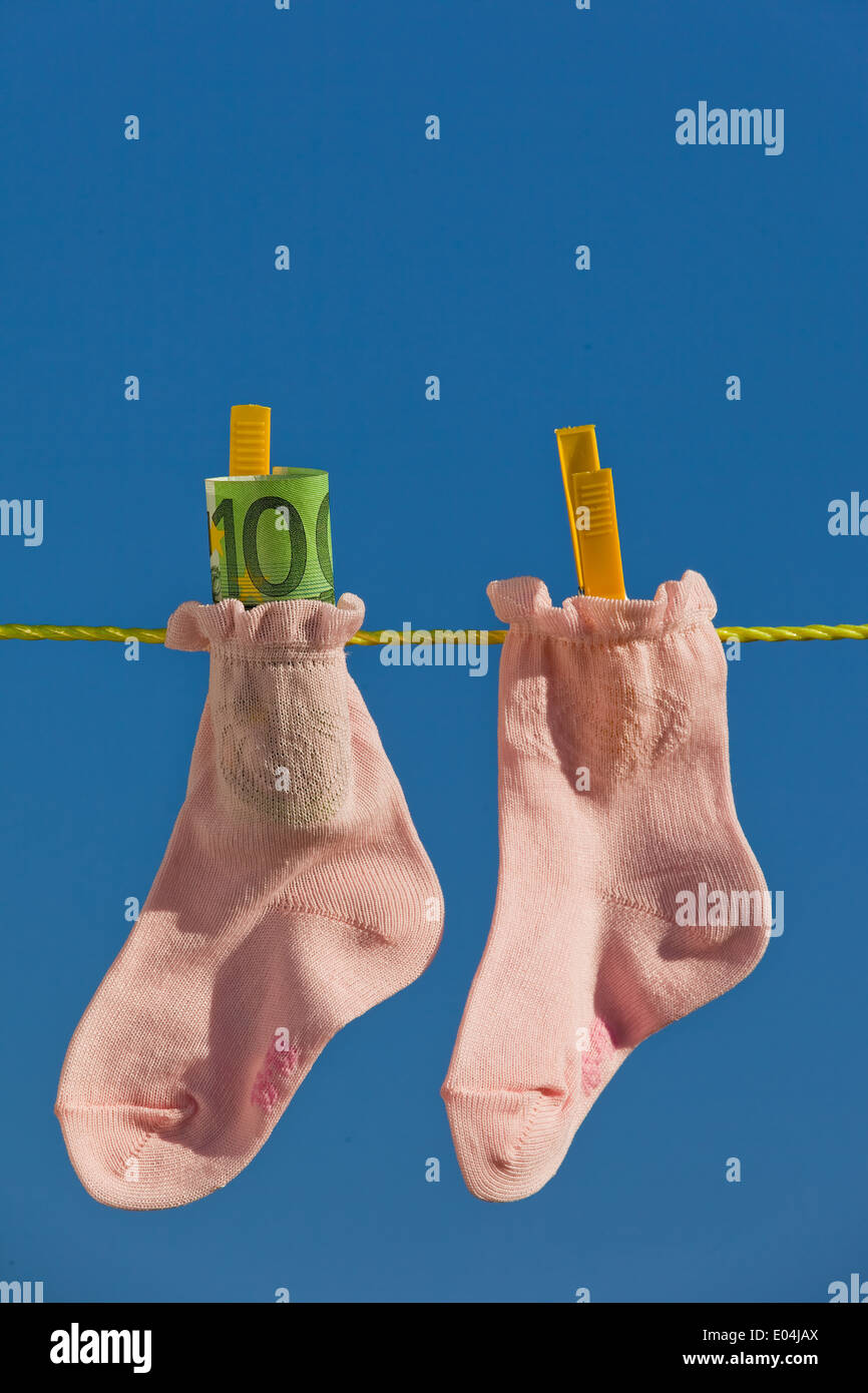 Baby socks on clothesline with eurobank notes. Blue sky., Baby Socken