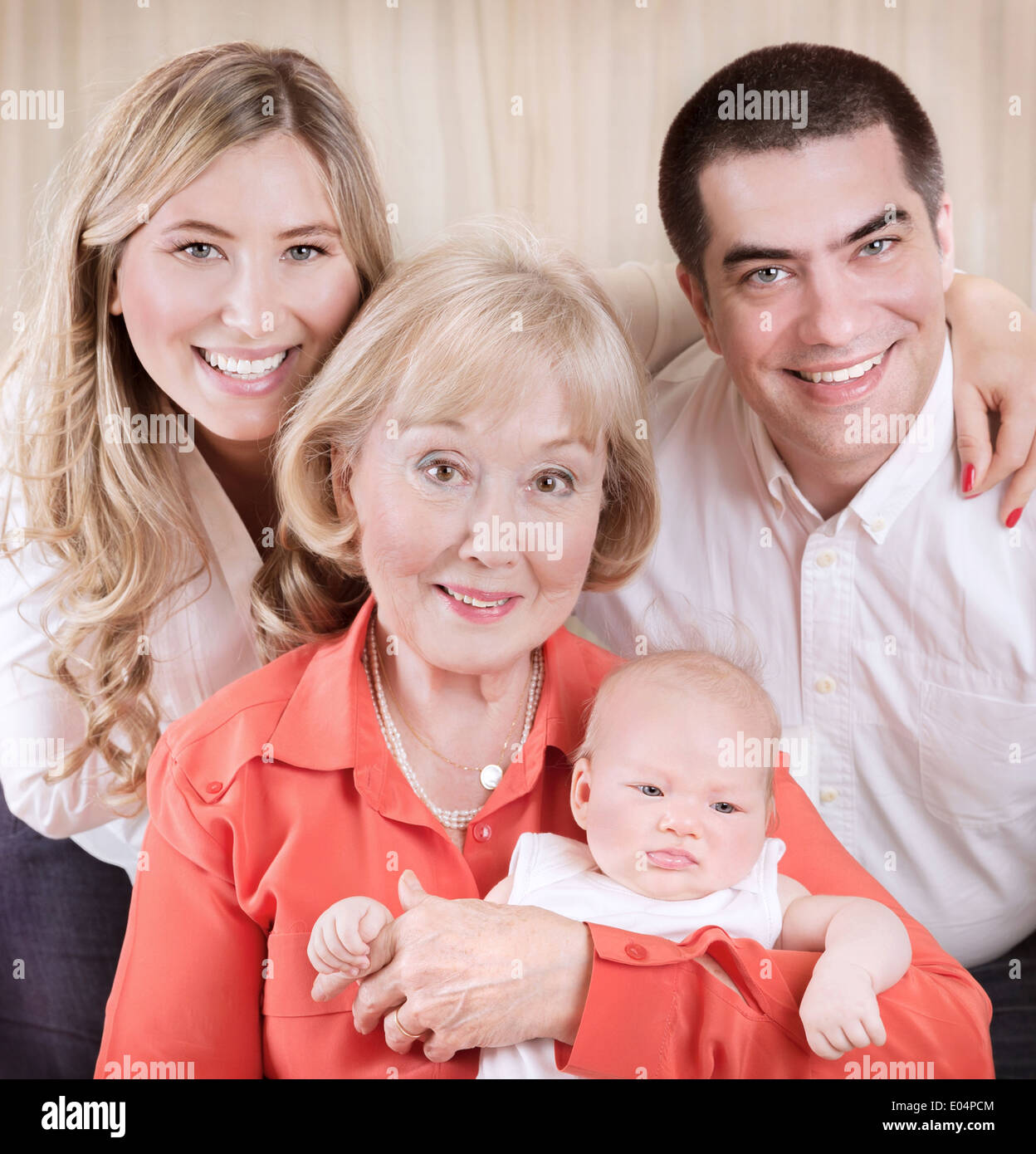 Family generation portrait, grand mother holding on hands newborn granddaughter, mother and father standing behind them Stock Photo