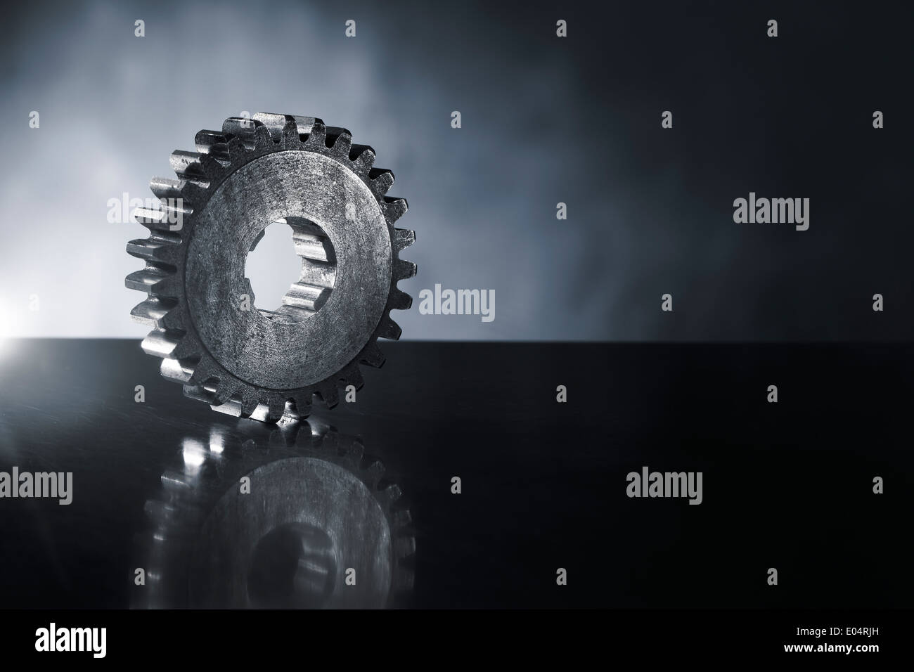 Old cog gear wheel on reflecting metal background. Short depth-of-field. Stock Photo