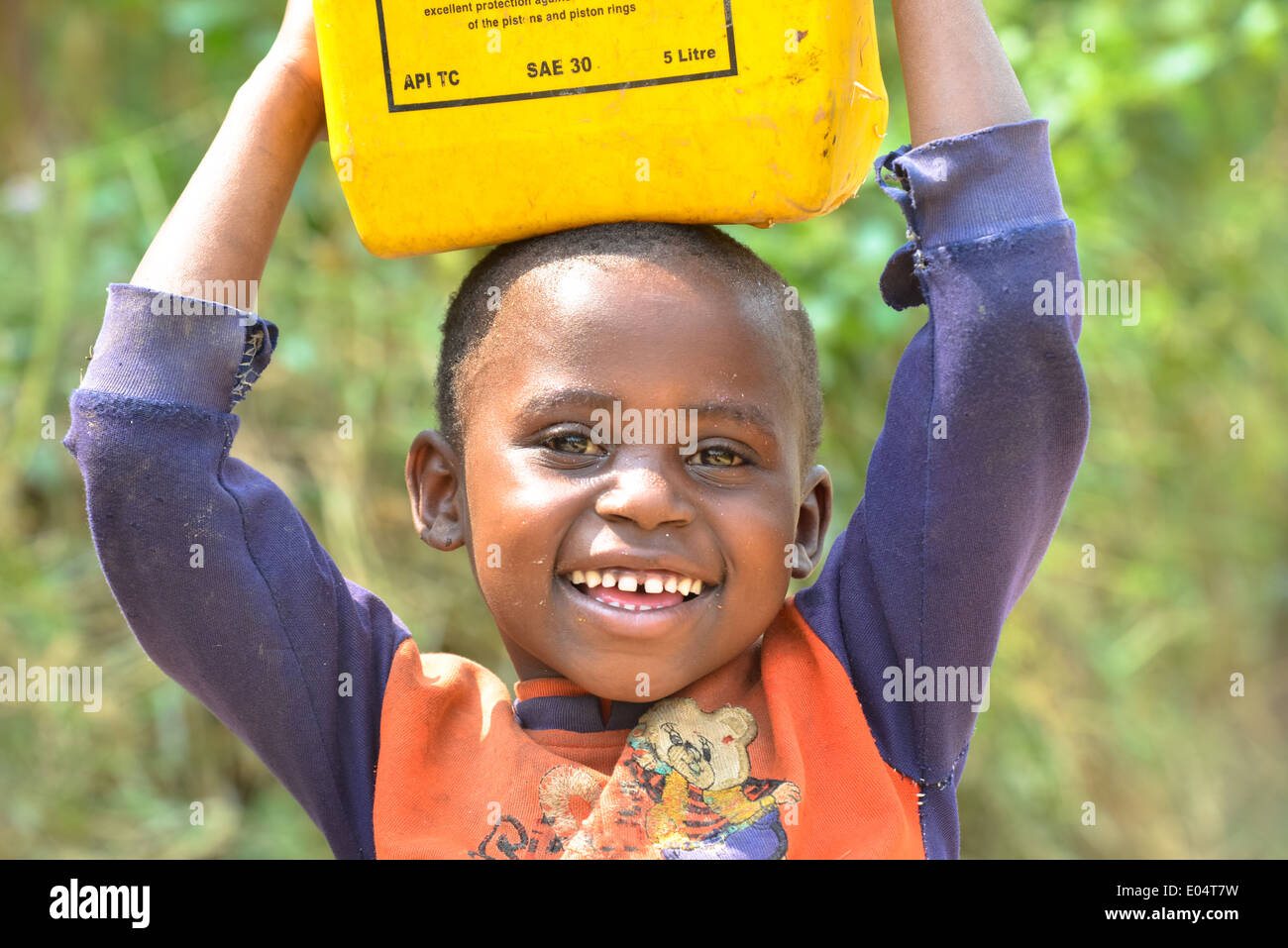 a ugandese boy carries a oil jerrycan on his head Stock Photo