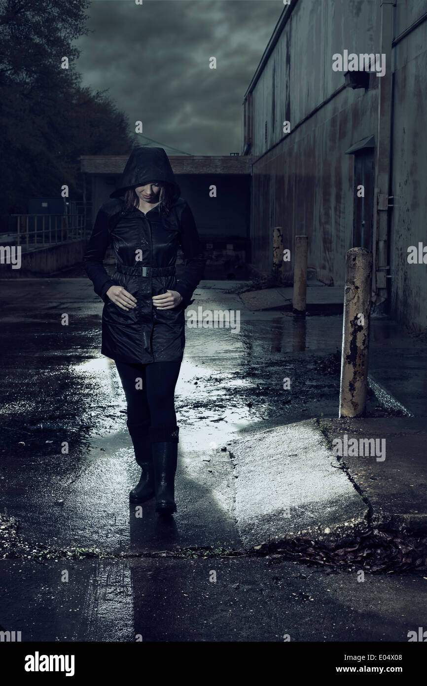 Woman in dark coat walking in rain Stock Photo