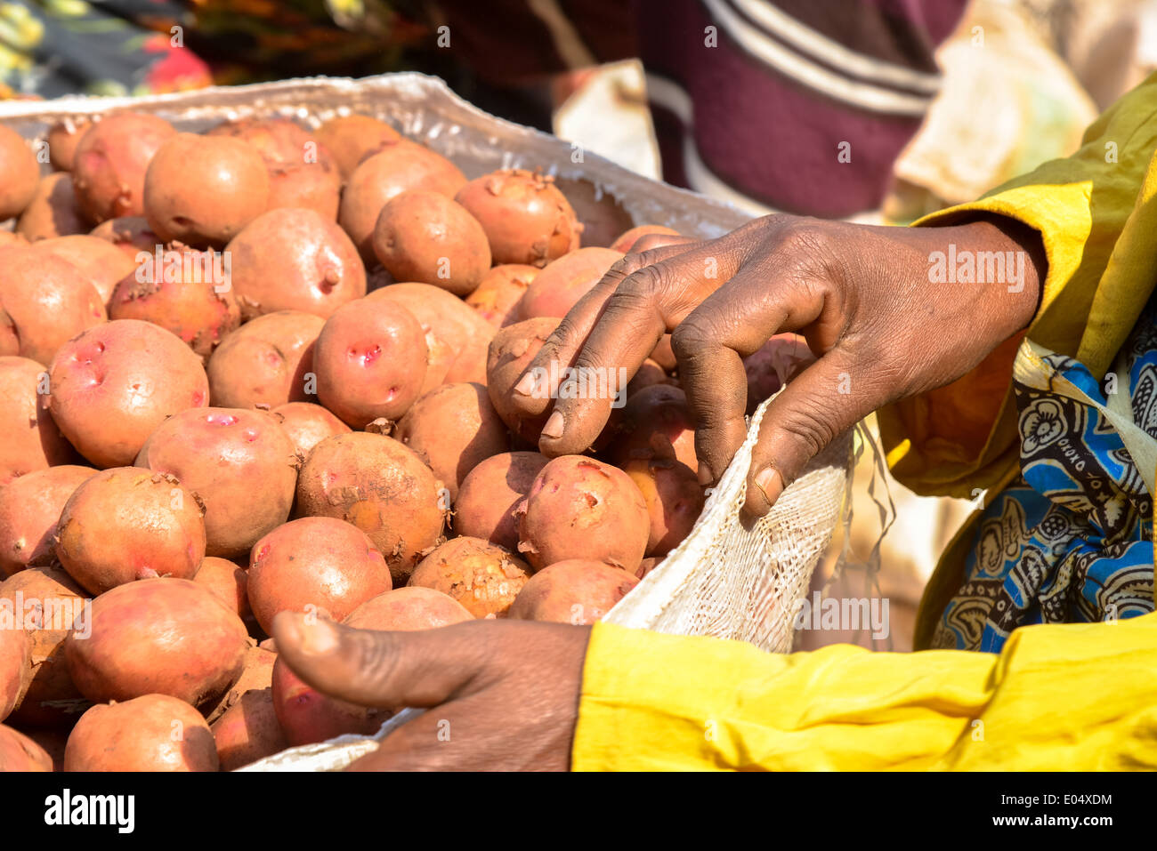 woman with sweet potatoes at marketplace at crater lake bunyonyi in uganda, africa Stock Photo