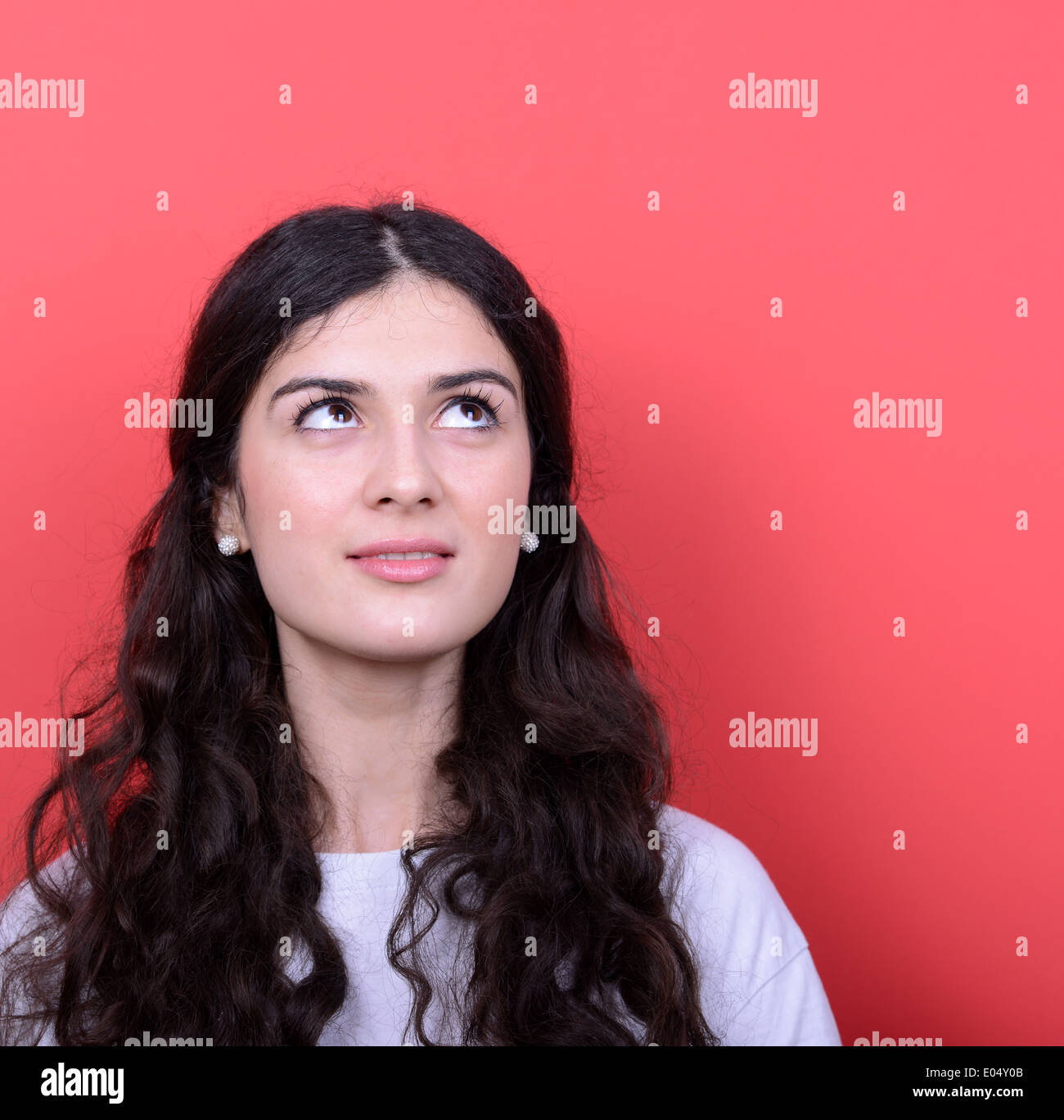Portrait of beautiful girl looking up against red background Stock ...