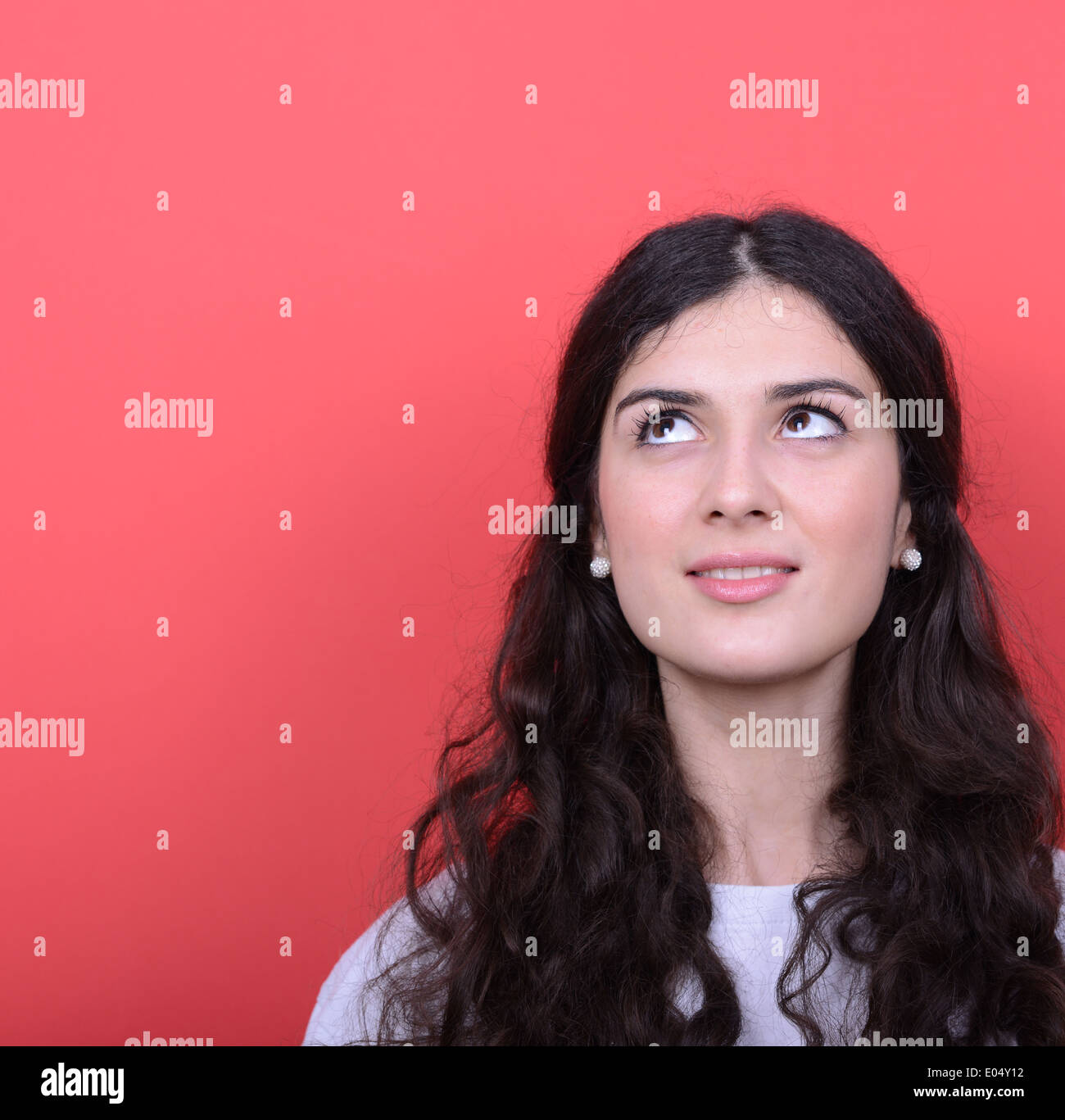 Portrait of beautiful girl looking up against red background Stock ...