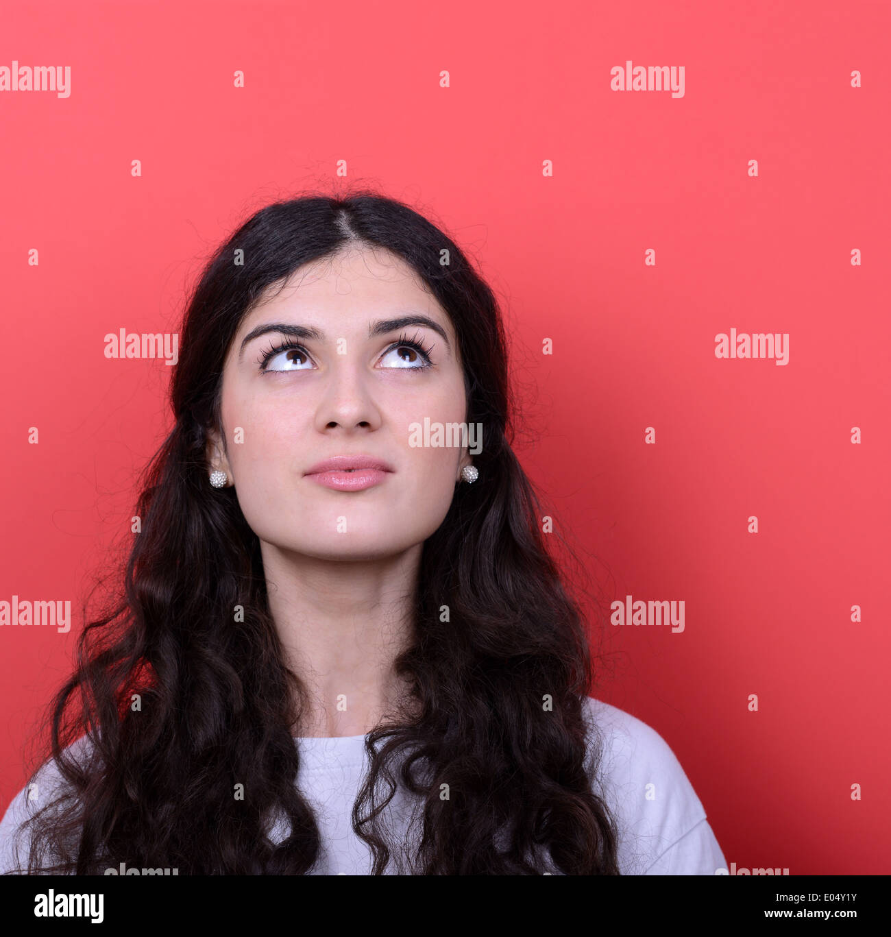 Portrait of beautiful girl looking up against red background Stock ...