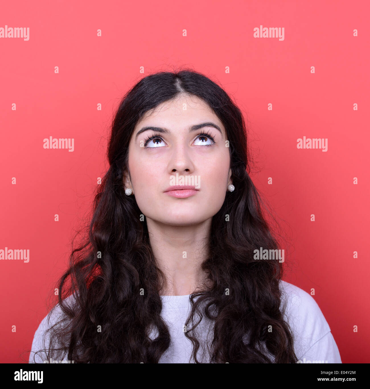 Portrait of beautiful girl looking up against red background Stock ...
