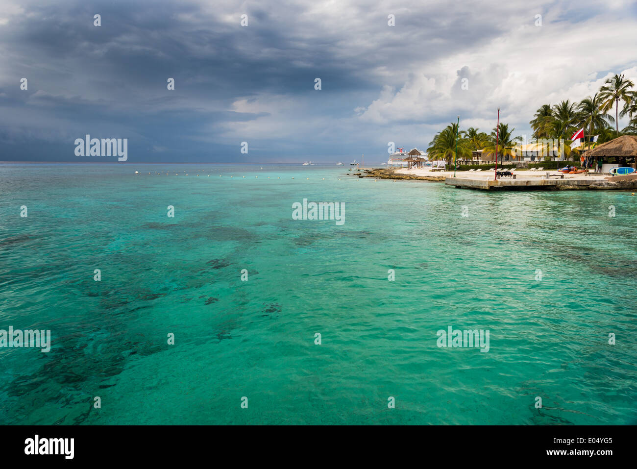 Palm trees and grass huts at a beach resort. Cozumel, Mexico. Stock Photo