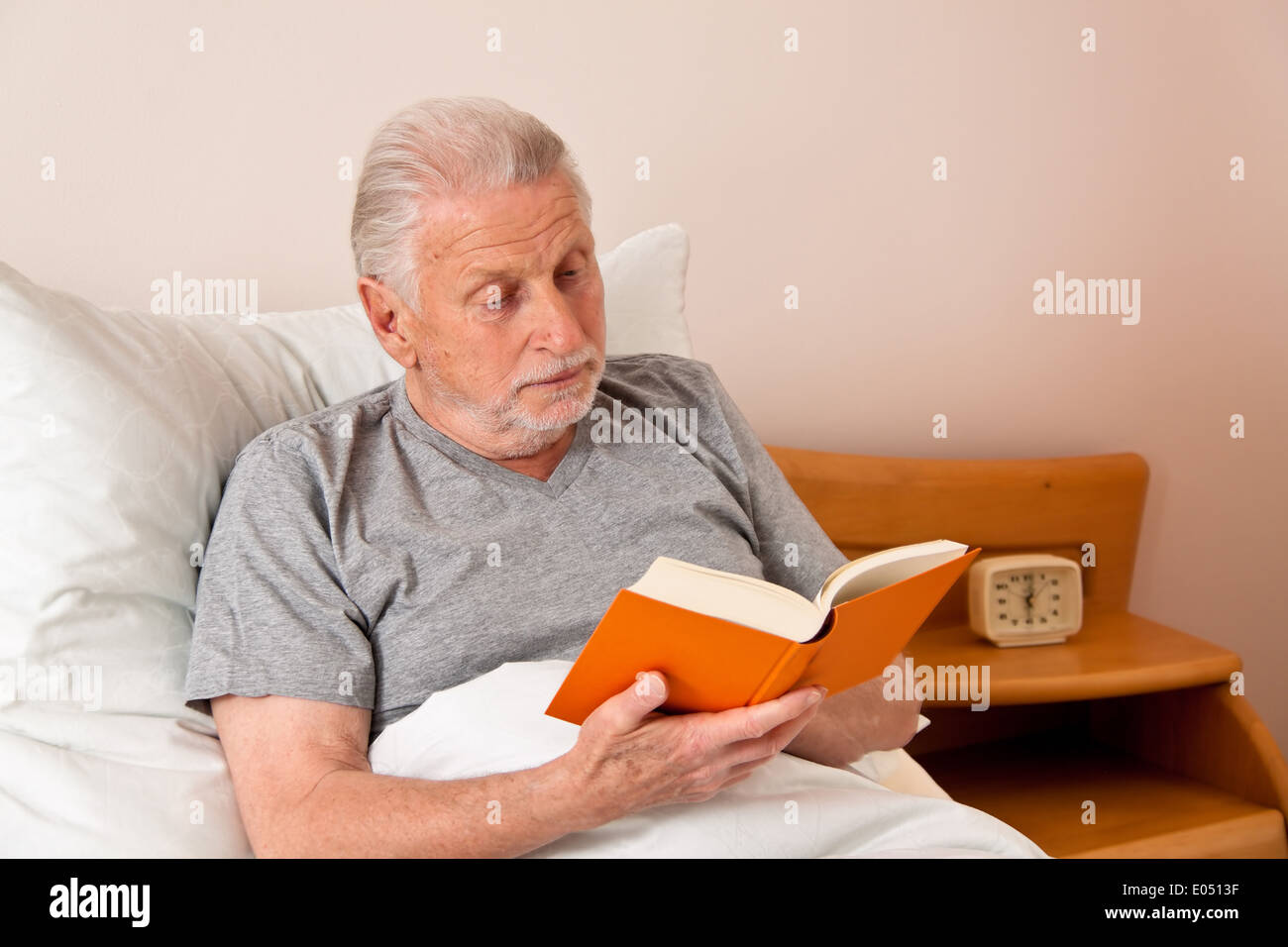 a boss in the old people's home with the book read in the bed, ein Senior im Altenheim beim Buch lesen im Bett Stock Photo