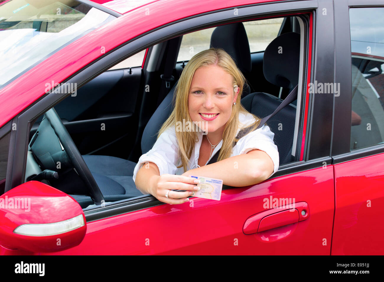 A young woman shows proudly her driving licence. Driving licence and new car., Eine junge Frau zeigt stolz ihren Fuehrerschein. Stock Photo