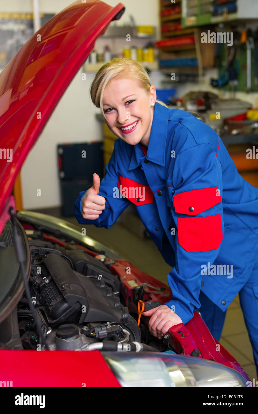 A young woman as a mechanic in a garage. Rare occupations for women. Car is repaired in workshop, Eine junge Frau als Mechaniker Stock Photo