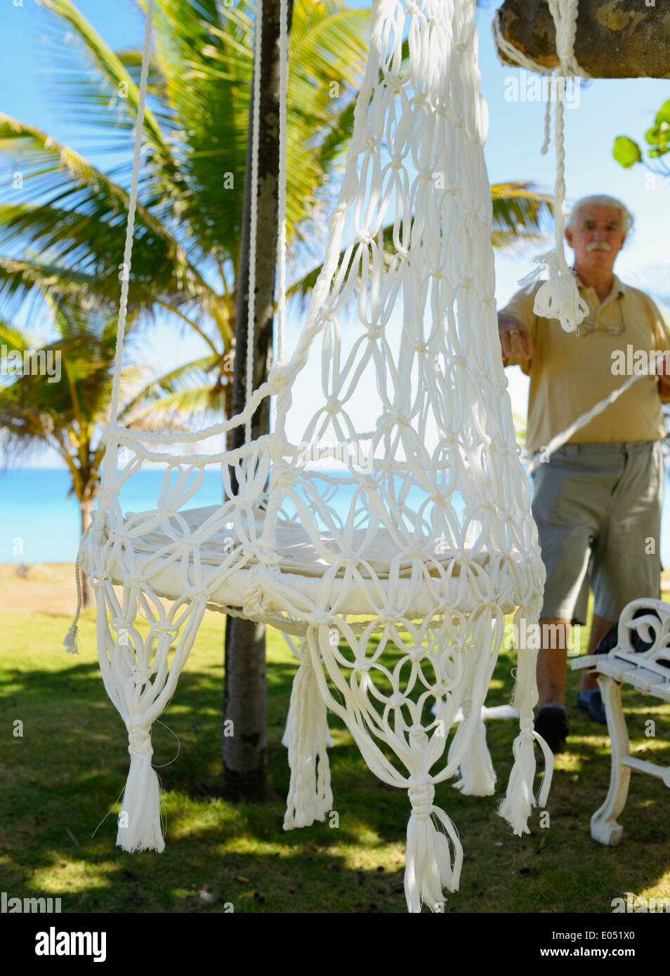 Cuban craftsman tying new white hammocks by the sea shore in Varadero