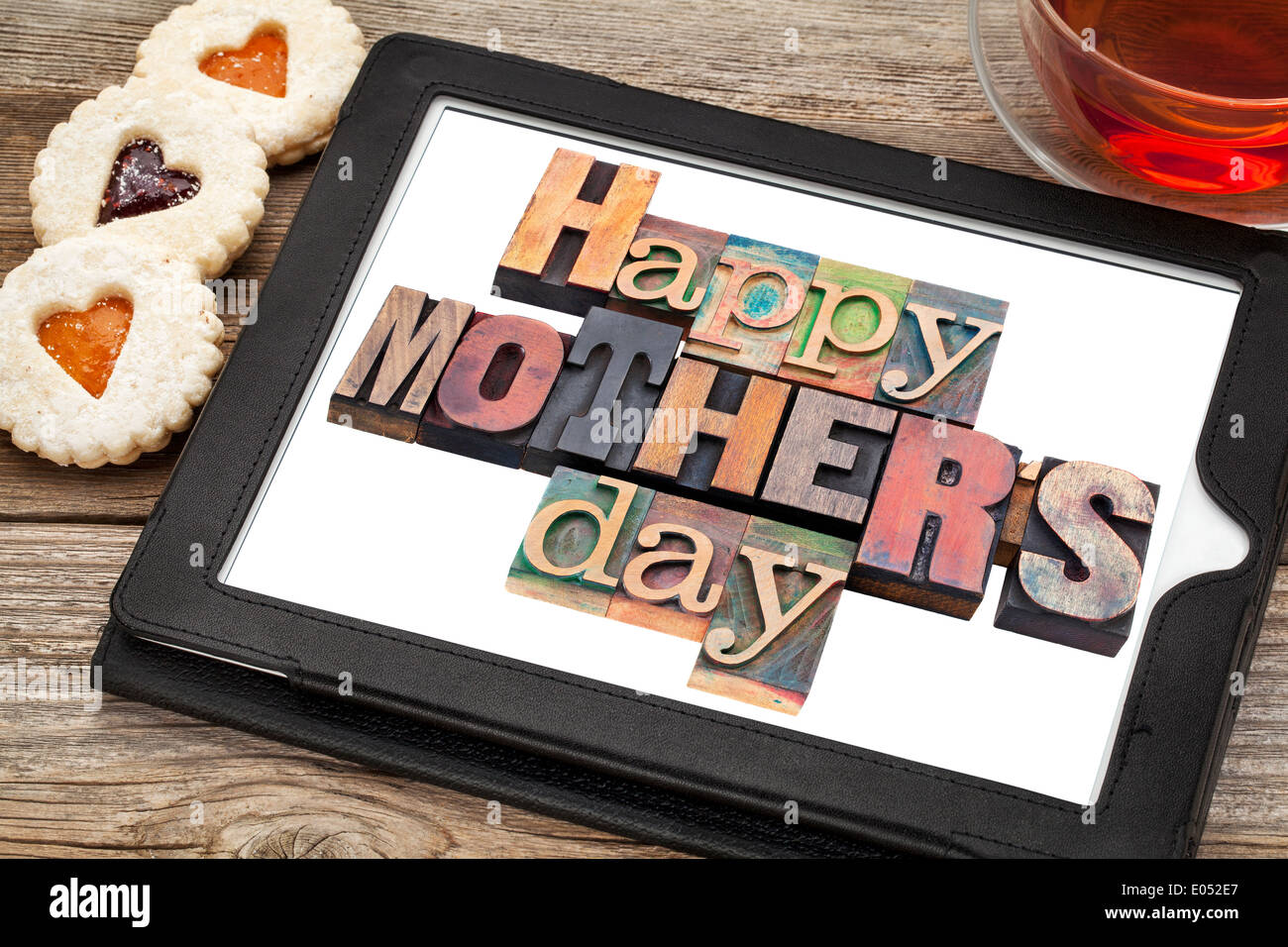 Happy Mother Day in vintage letterpress wood type on a digital tablet with a cup of tea and heart cookies Stock Photo