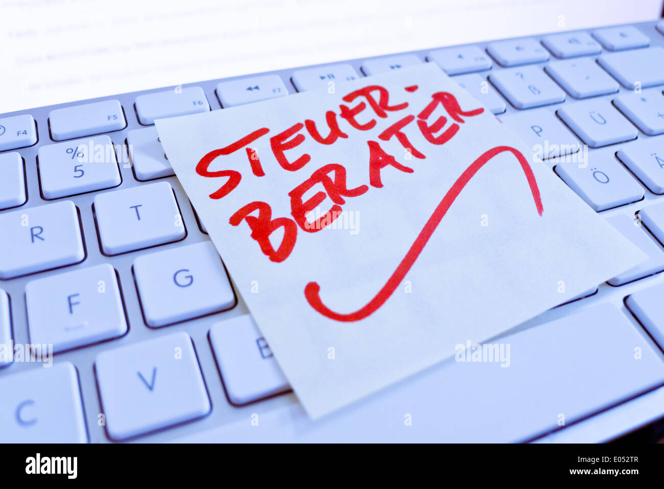 A note slip of paper lies on the keyboard of a computer in memory: Tax adviser, Stock Photo