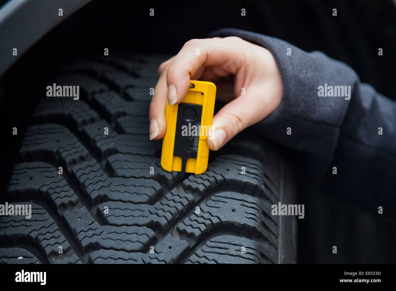A young woman misses the profile depth of her tyre. The right depth in the  profile of a tyre can prevent accidents., Eine junge Stock Photo - Alamy