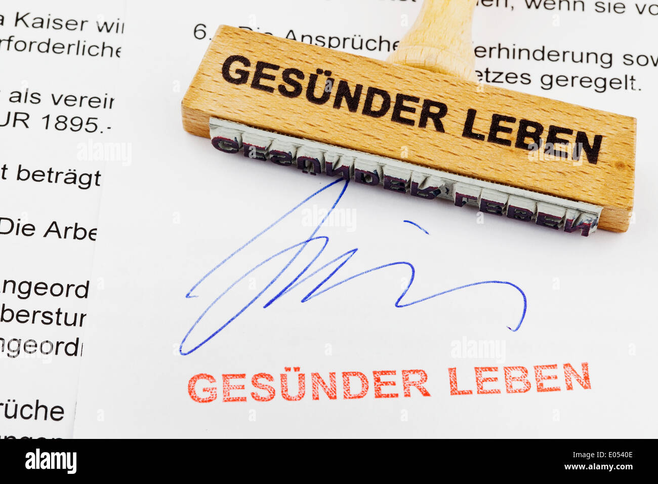 A stamp of wood lies on a document. German label: healthier live, Ein Stempel aus Holz liegt auf einem Dokument. Deutsche Aufsch Stock Photo