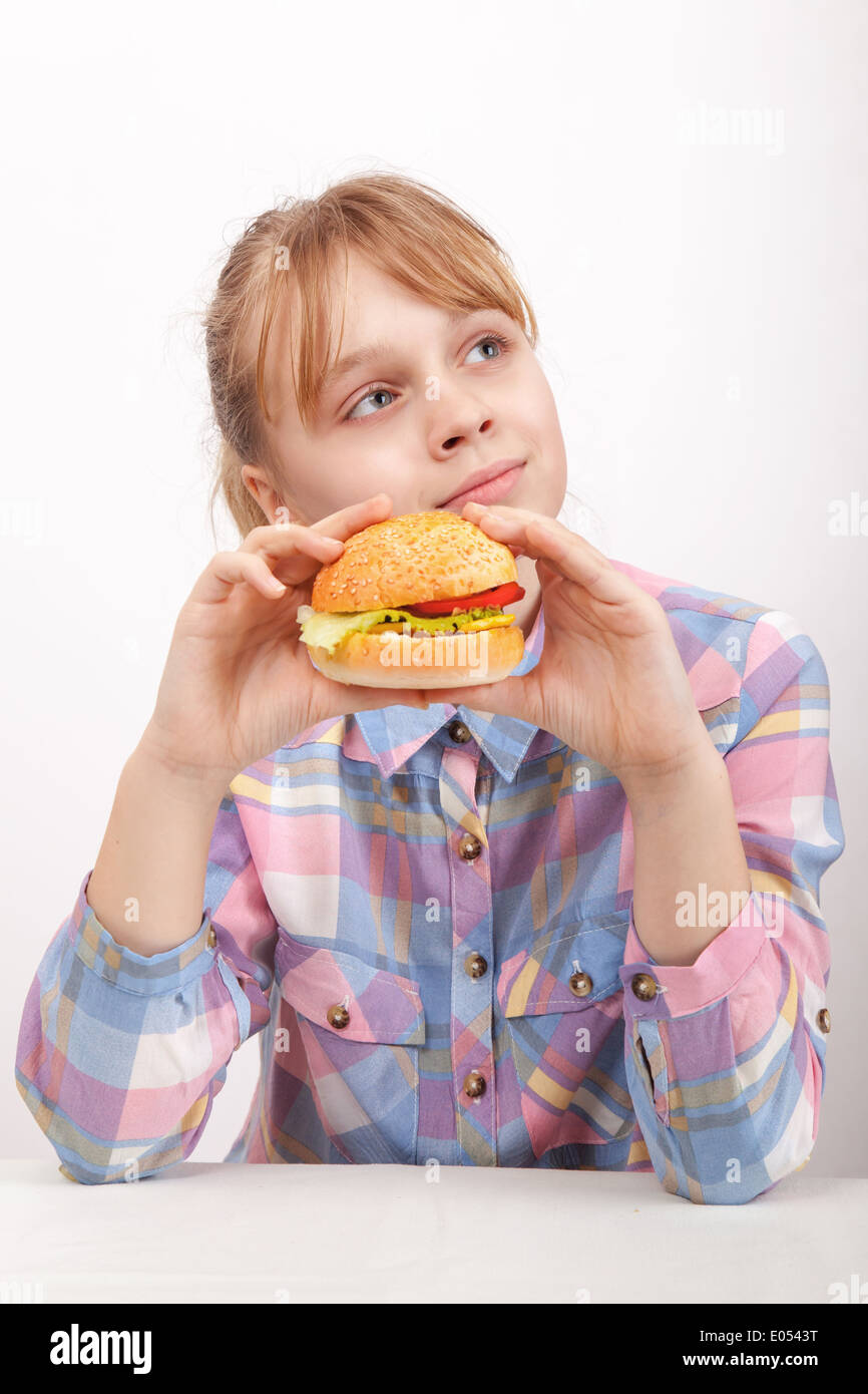 Little blond girl with homemade hamburger on white background Stock Photo