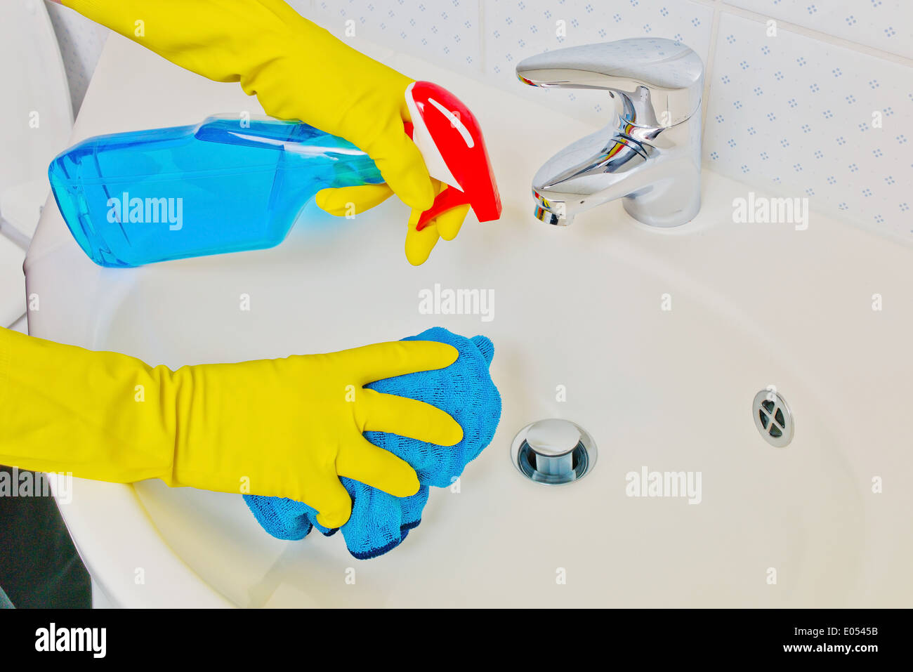 The wash basin of a bathroom is cleaned with latex to gloves., Das Waschbecken eines Badezimmers wird mit Latex Handschuhen gere Stock Photo