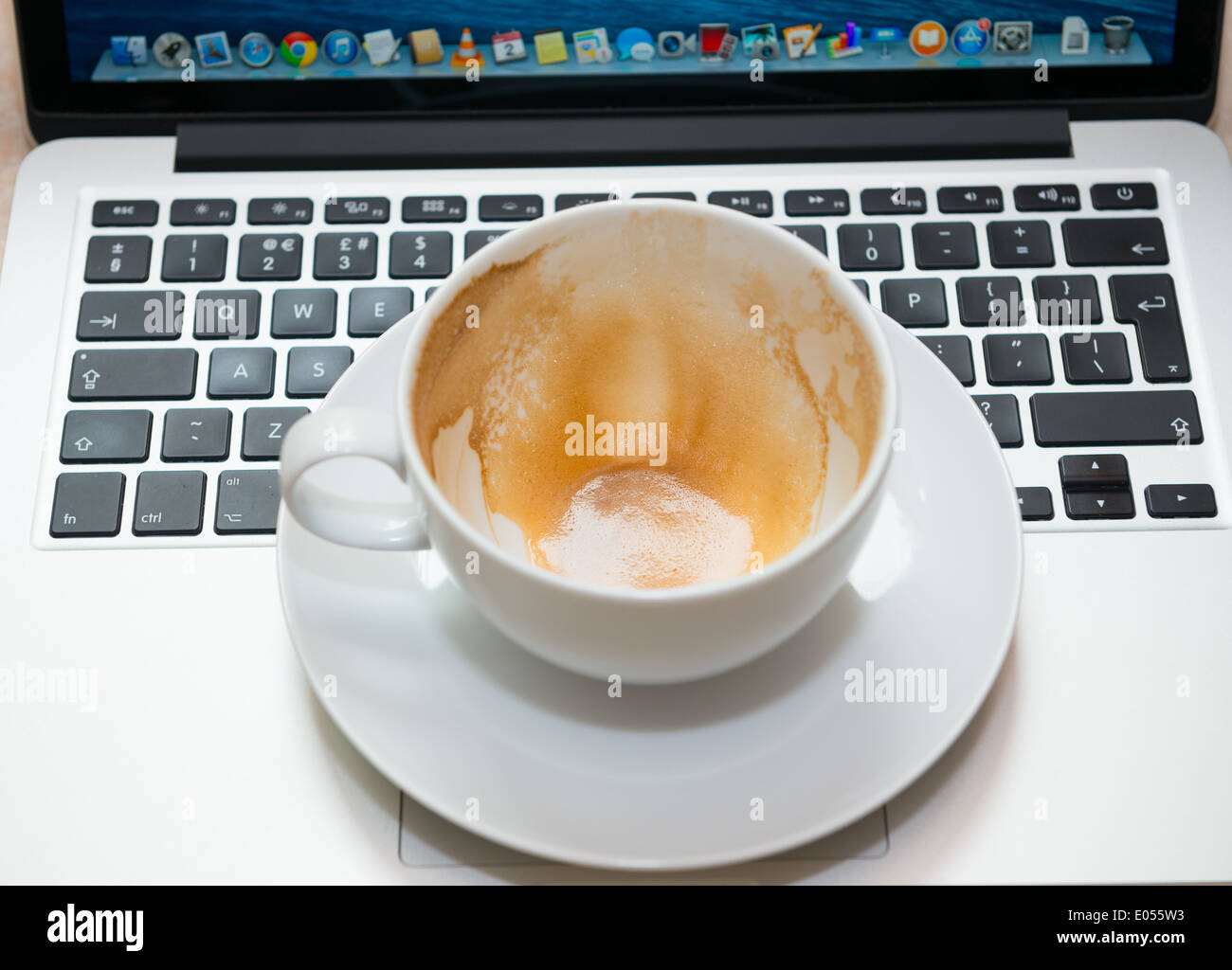 An empty cappuccino cup and saucer on a laptop Stock Photo