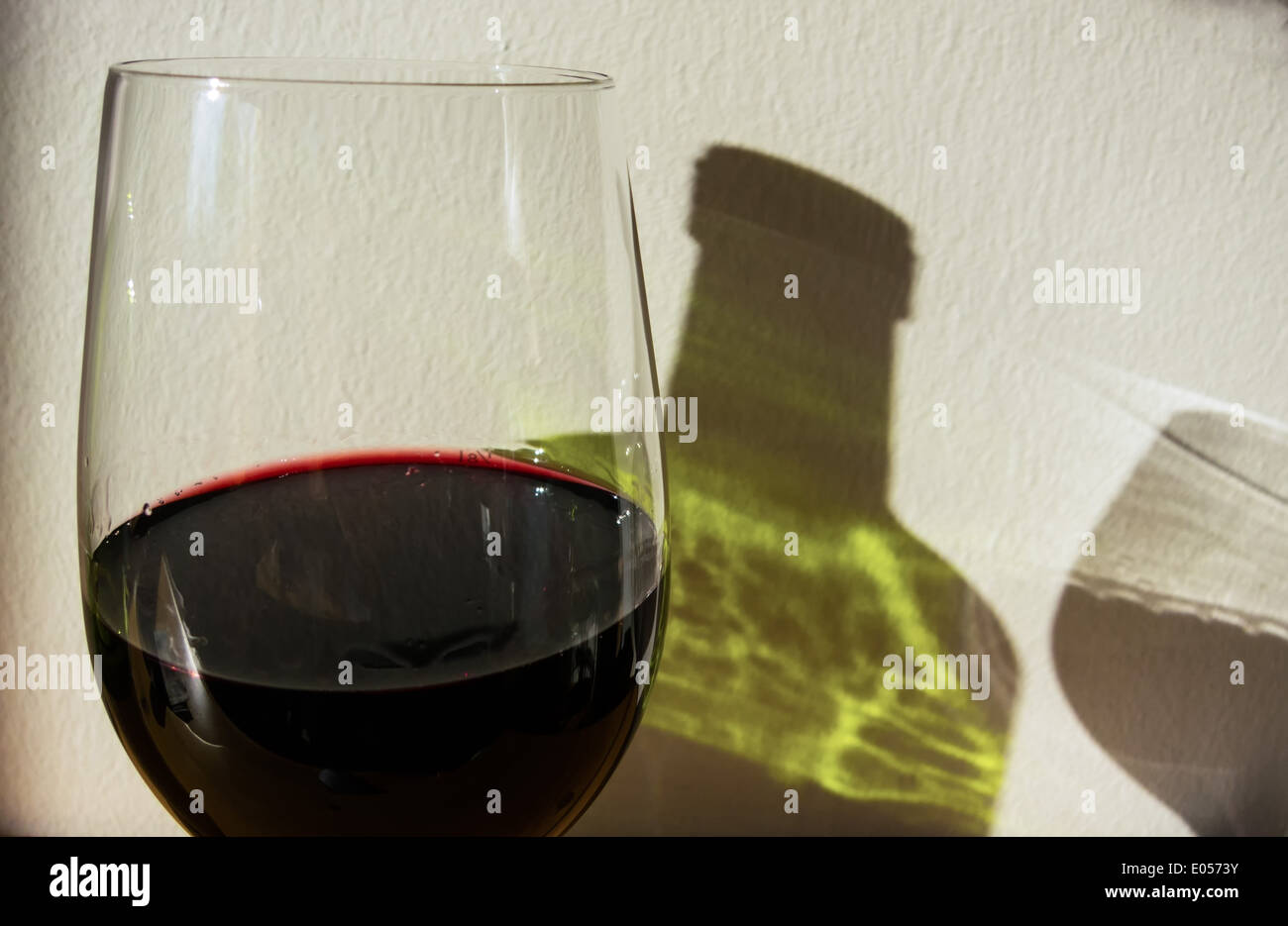 The shade of a red wine bottle and a red wineglass on a wall, Der Schatten einer Rotweinflasche und eines Rotweinglases auf eine Stock Photo
