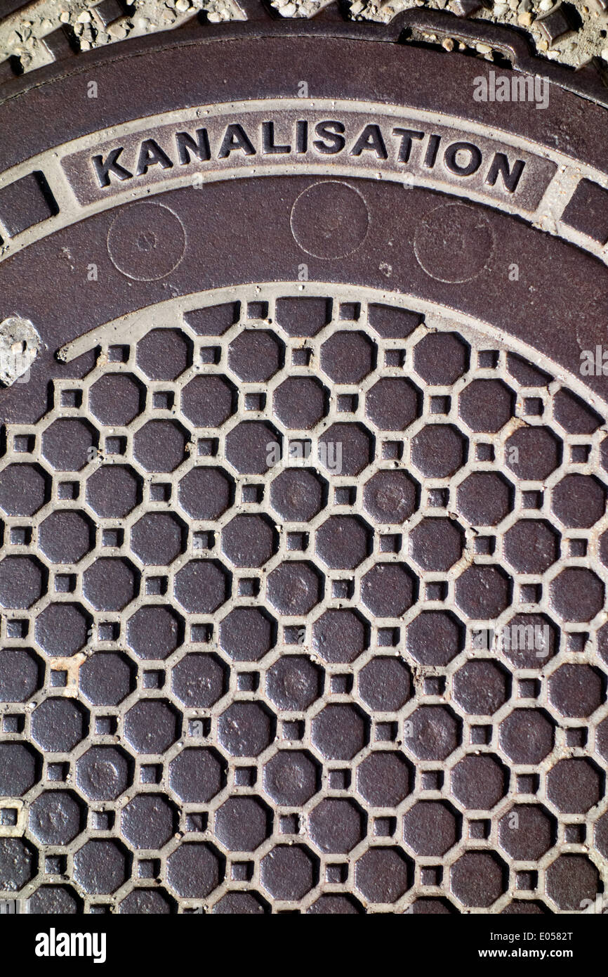The lid of a canalisation on a street. , Der Deckel einer Kanalisation auf einer Strasse. Stock Photo