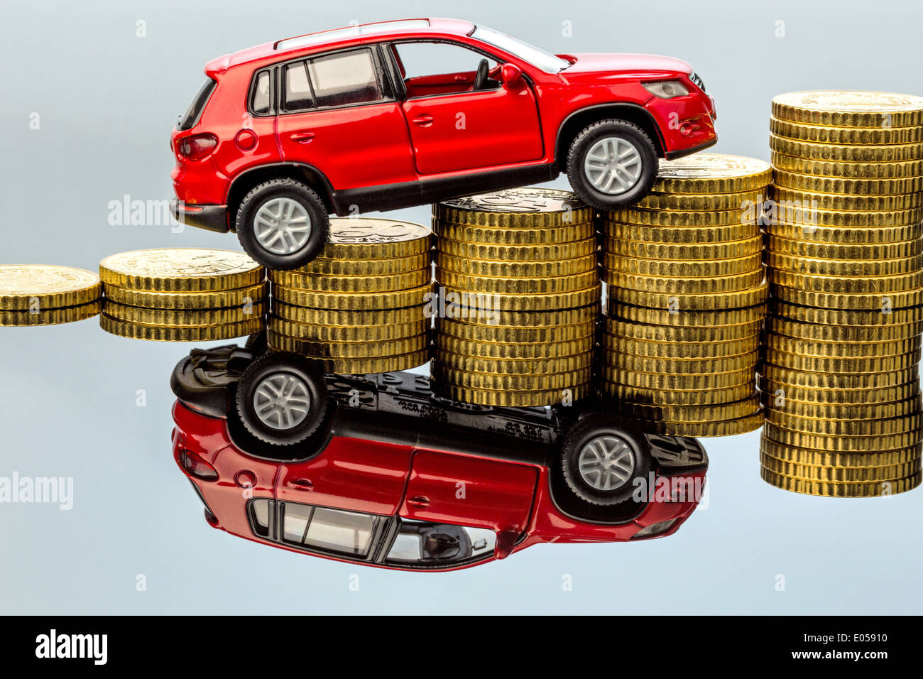 Rising autocosts. A car takes up a coin pile, Steigende Autokosten. Ein Auto fuehrt einen Muenzstapel hinauf Stock Photo