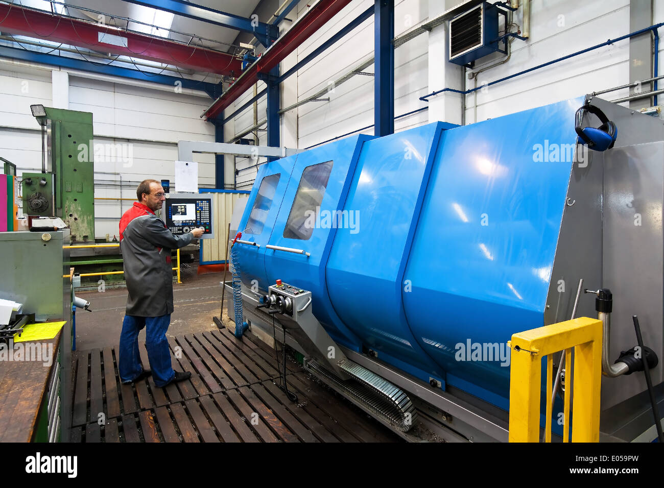 An older employee of the metal industry in milling machine CNC., Ein aelterer Arbeitnehmer der Metallindustrie an CNC Fraesmasch Stock Photo