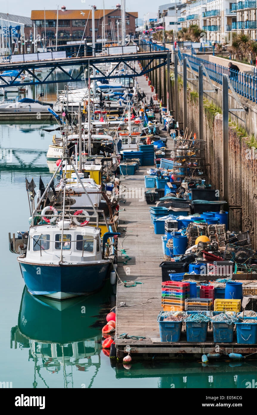 A busy and cluttered jetty lined with fishing boats and equipment in