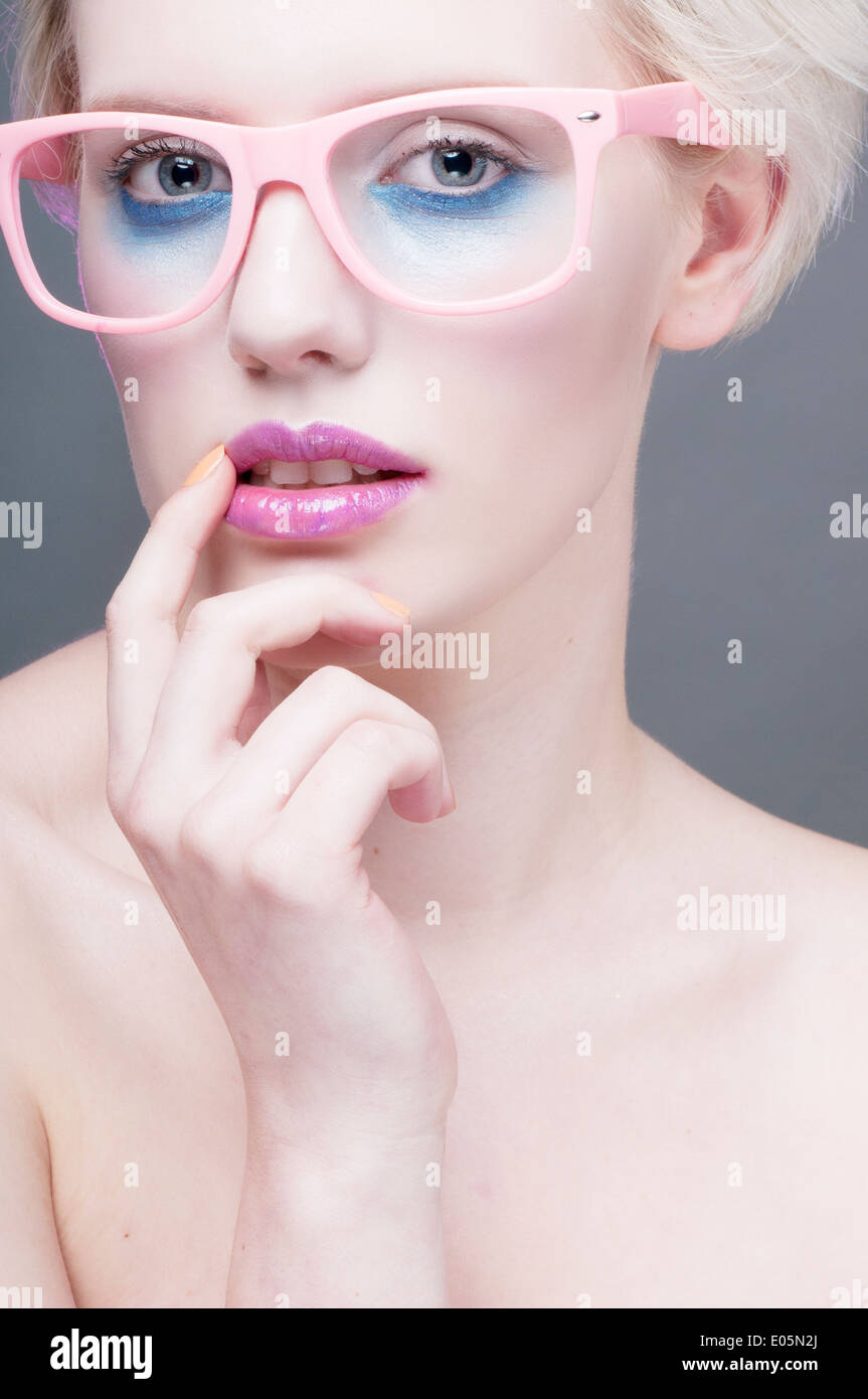 Fashion headshot portrait of a Caucasian young woman in bright make-up wearing pink glasses Stock Photo