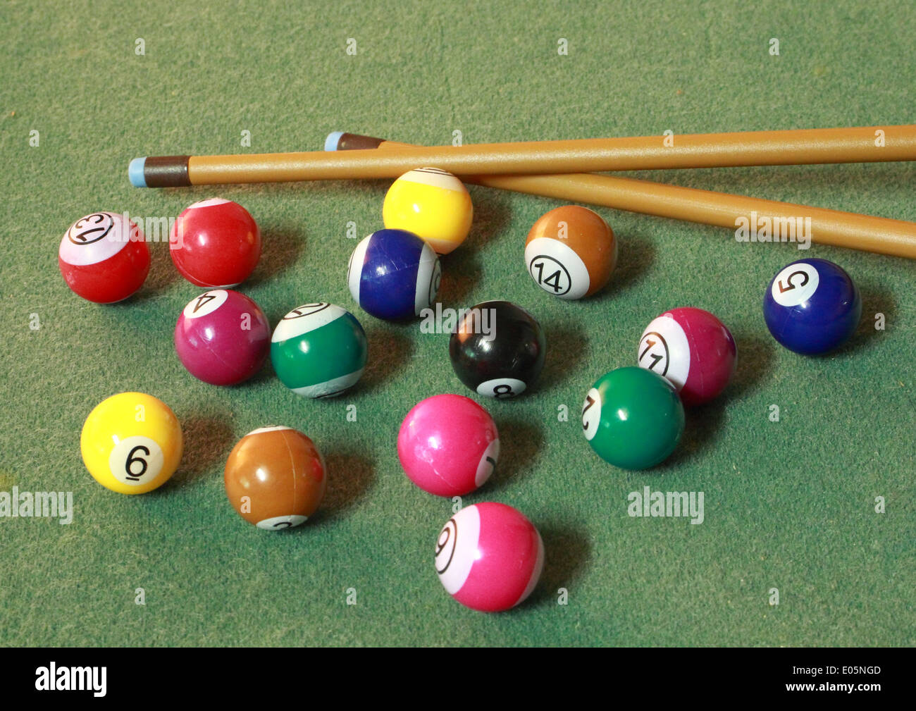 Pool balls on green cloth in disorder with cues Stock Photo