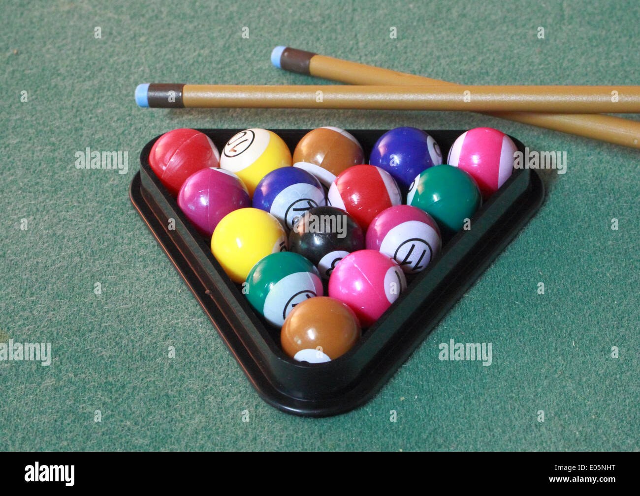 Pool balls on green cloth in triangle with cues Stock Photo