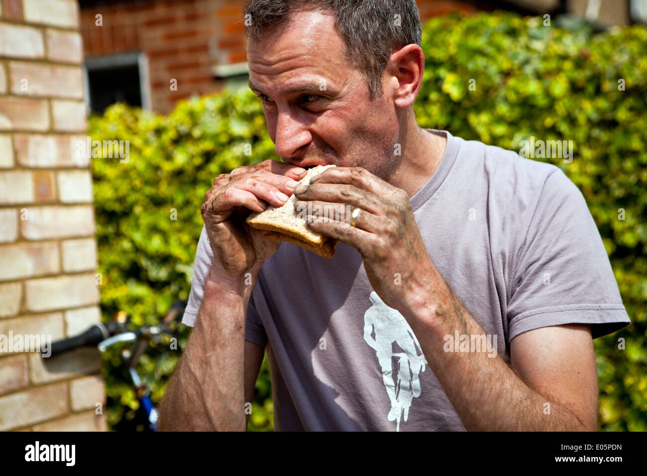 Man eating sandwich with dirty hands Stock Photo