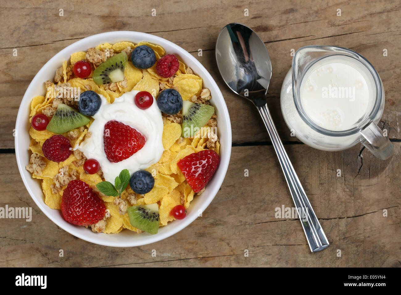 Fruit cereals with yogurt and milk, strawberries, raspberries, kiwi and blueberries from above Stock Photo