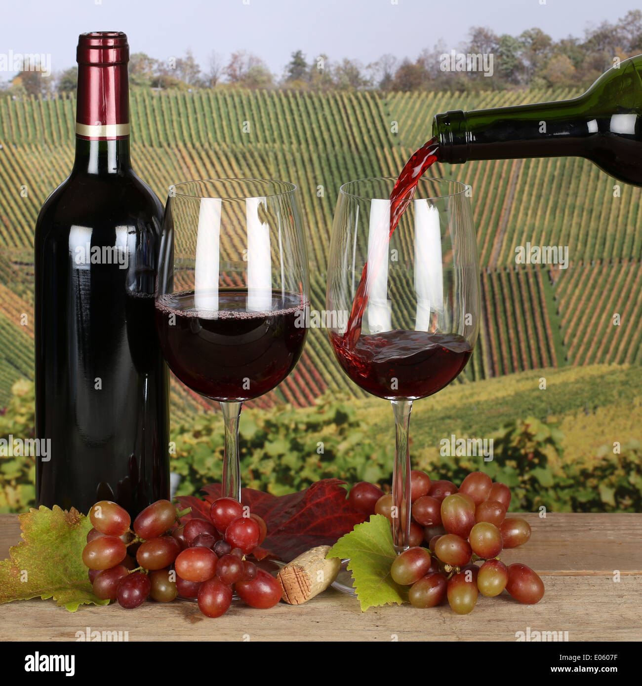 Red wine pouring from a bottle into a glass in the vineyards Stock Photo