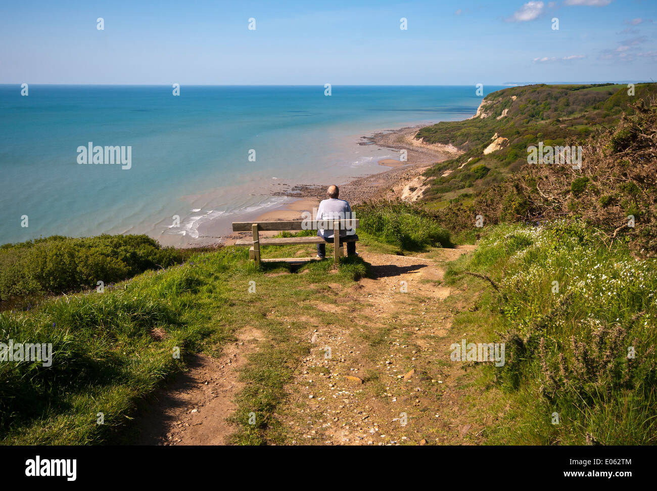 Man Sat on a Bench Looking Out to Sea Depicting Solitude Isolation and Loneliness Stock Photo