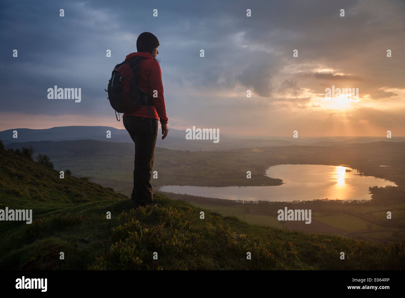 Female hiker takes in view of Llangorse lake from Mynydd Llangorse, Black Mountains, Brecon Beacons national park, Wales Stock Photo