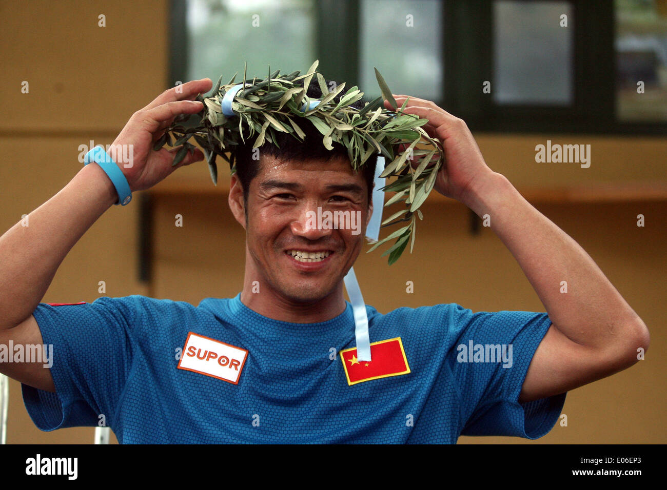 Athens, Greece. 4th May, 2014. Chinese runner Chen Penbin, who finished third at the 3rd Dolichos Ultra Marathon is awarded with an olive wreath in front of the ancient Stadium of Olympia, Greece, on May 4, 2014. A total of 26 athletes started on Friday running nonstop a 255 kilometers race from Delphi in mainland Greece to the birthplace of the Olympic Games. © Marios Lolos/Xinhua/Alamy Live News Stock Photo